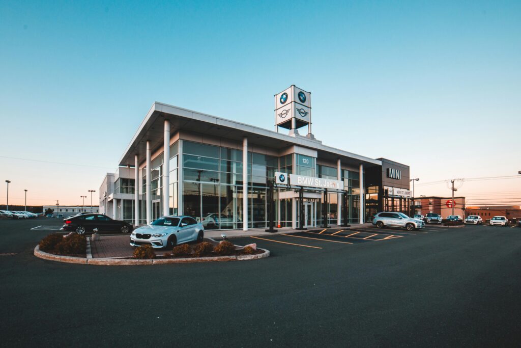 A modern BMW car dealership in a city with luxury cars and clear blue sky.